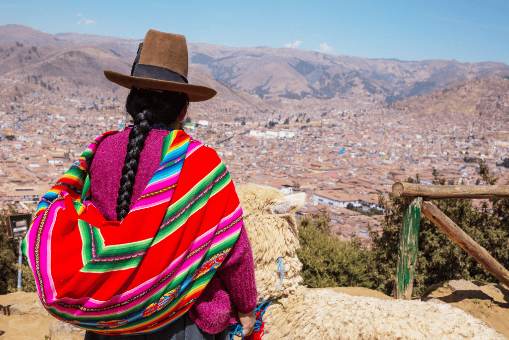 Mujer peruana con vestimenta tradicional junto a una llama, en Cusco.