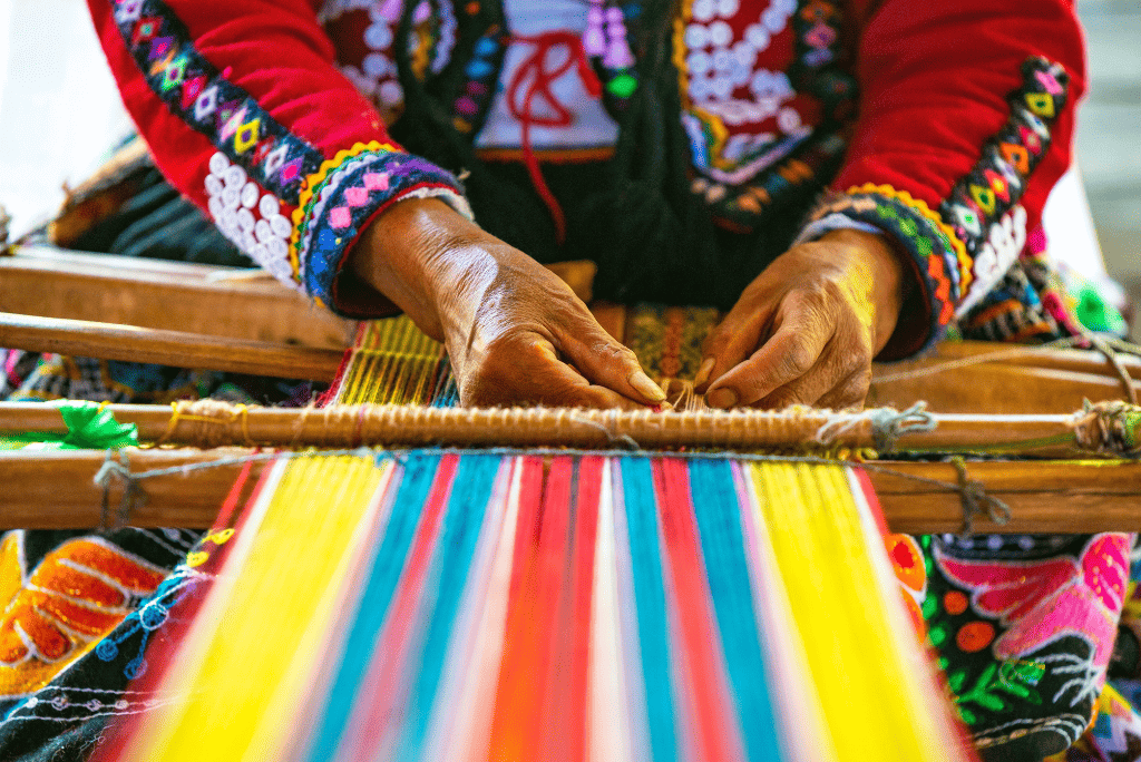 Manos tejiendo textiles coloridos en Perú.